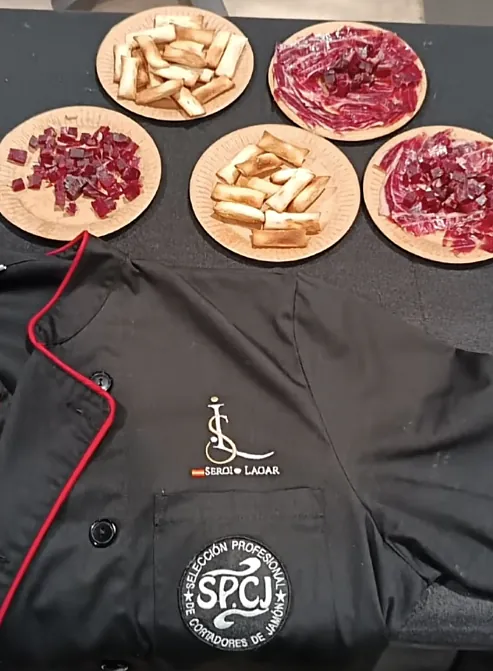 Chaquetilla de cortador profesional junto a raciones de jamón y picos